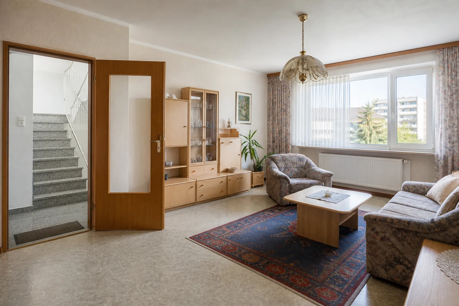 Heller älterer Wohnraum mit Blick durch die Wohnungstür in das gemeinsame Stiegenhaus